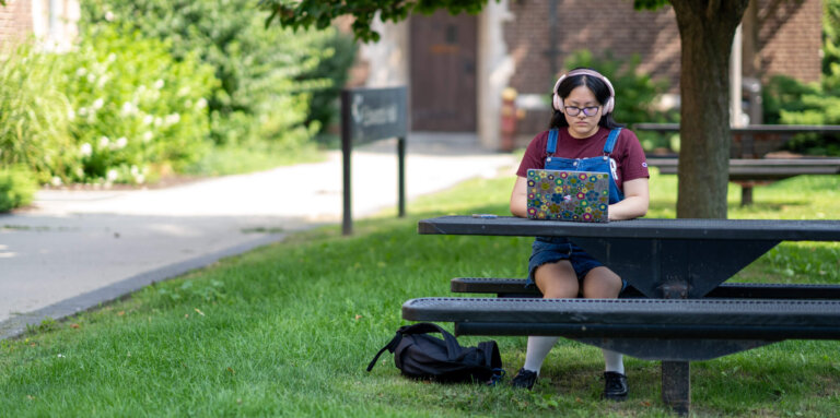 Student outside at a picnic table studying.